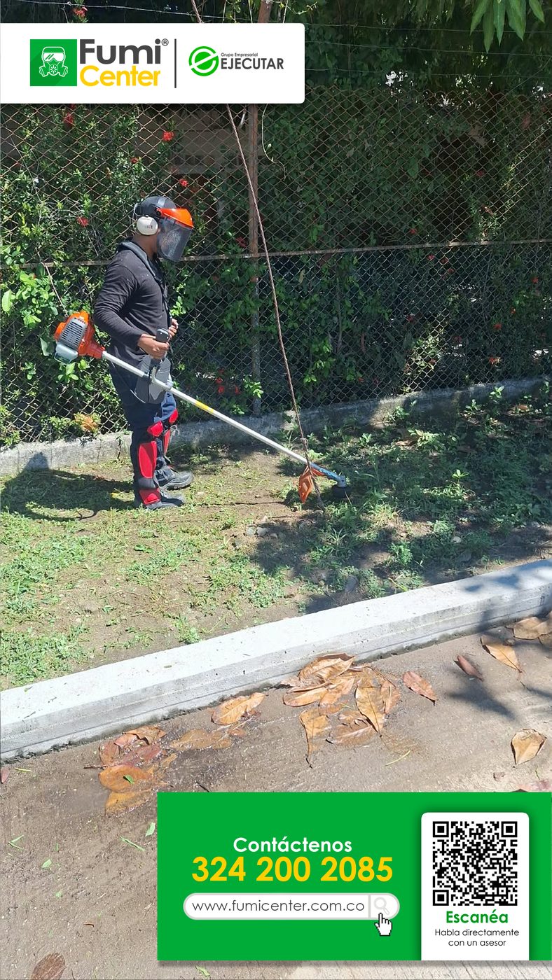 Operario de FumiCenter con guadaña y careta cortando el césped de la zona verde de un conjunto en Santa Marta